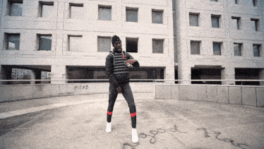 a man is standing in front of a building with graffiti on it that says acab