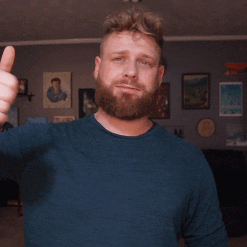 a man with a beard gives a thumbs up sign