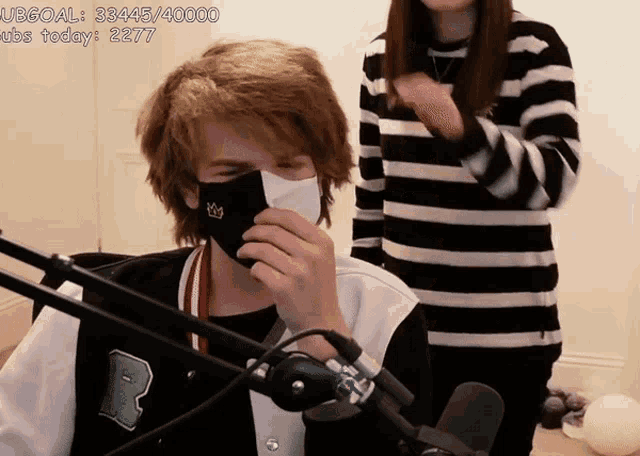 a man wearing a mask with a crown on it stands next to a woman wearing a striped shirt