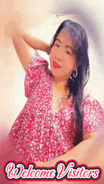 a woman in a pink floral shirt is standing in front of a sign that reads welcome visitors