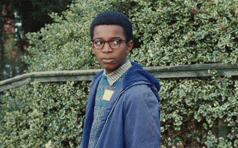 a boy wearing glasses and a blue jacket has a name tag on his shirt