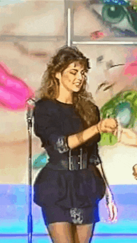 a woman is standing in front of a microphone and smiling