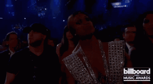 a woman is standing in a crowd at a billboard music awards