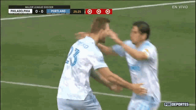 a soccer player with the number 23 on his back is hugging his teammate