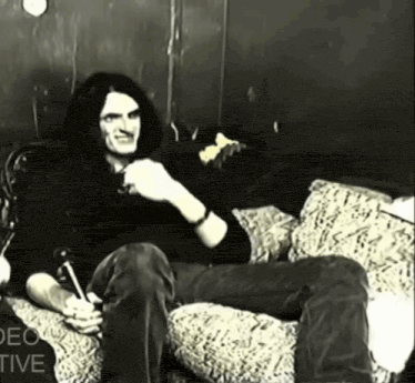 a black and white photo of a man sitting on a couch with the words video tive visible