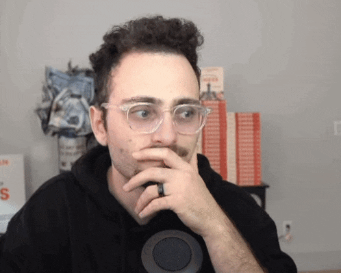 a man wearing glasses and a ring is looking at something