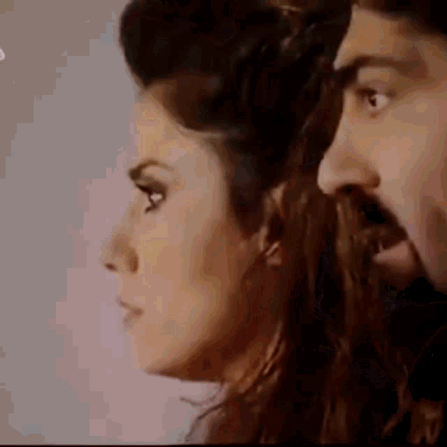 a man and a woman are looking at each other . the man has a beard and the woman has long hair .