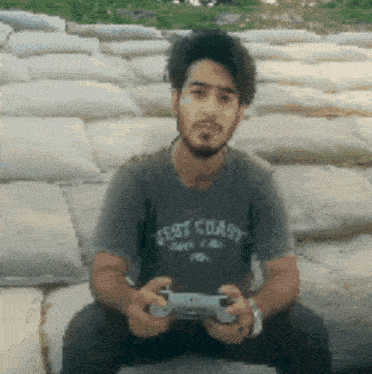 a man wearing a west coast shirt holds a video game controller