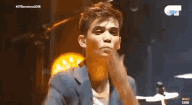 a man in a suit is blowing a kiss on a stage while playing drums .
