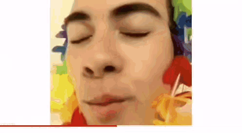 a close up of a man 's face with his eyes closed and a rainbow wig on his head .