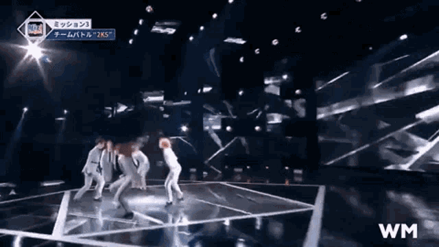 a group of people are dancing on a stage with a sign that says wm on it .