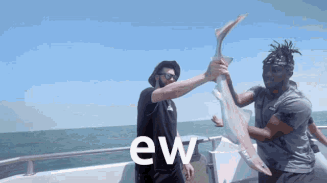 two men on a boat holding a large fish with the word ew in the corner