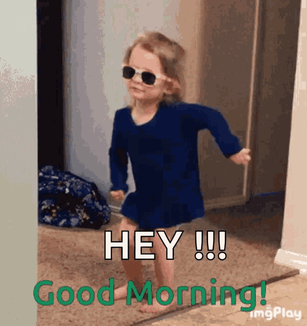 a little girl wearing sunglasses and a blue dress is dancing and saying good morning