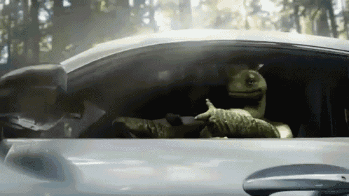 a lizard is sitting in the driver 's seat of a silver car