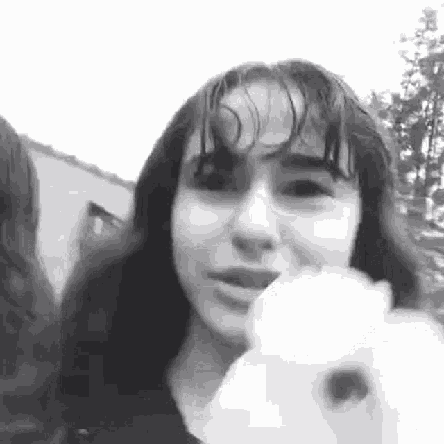 a black and white photo of a girl holding a stuffed animal in her hand .