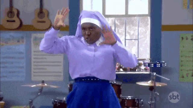 a woman in a nun costume is dancing in a classroom with drums and guitars .