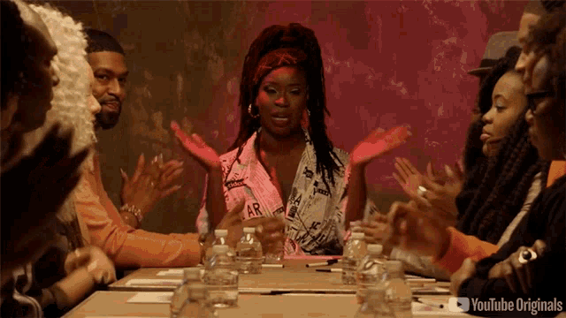 a group of people sitting around a table with bottles of water and a youtube originals logo in the corner