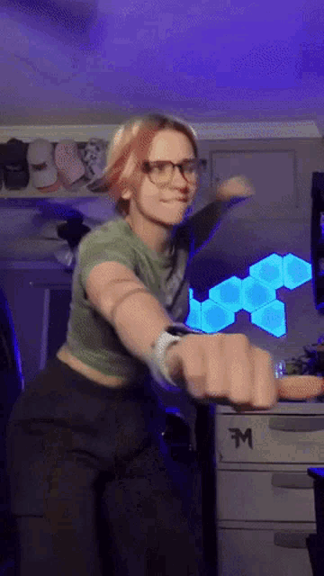 a woman wearing glasses is standing in front of a desk with the letter m on it