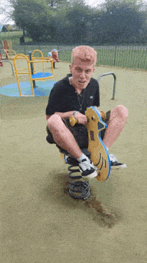 a boy sits on a rocking horse in a park