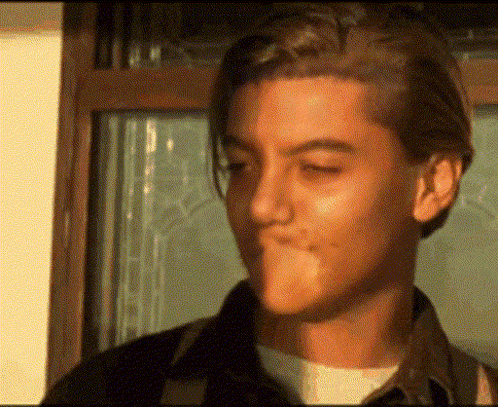 a young man with his eyes closed is blowing a bubble gum .