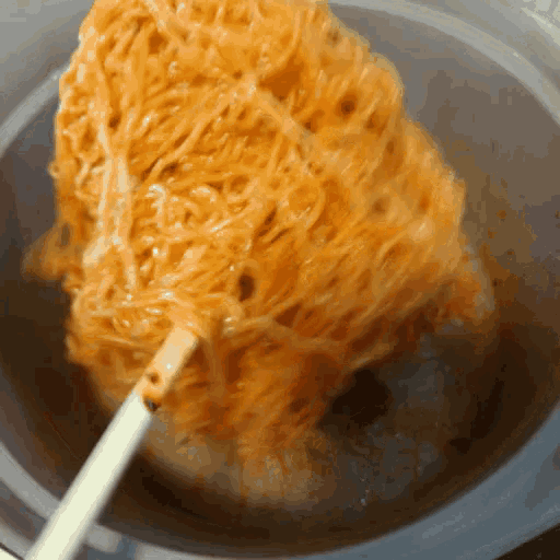 noodles are being stirred in a bowl with a stick