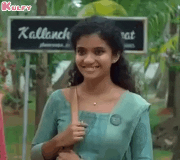 a woman in a blue dress is smiling in front of a sign that says kallanche .