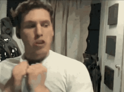 a man in a white shirt is adjusting his tie in front of a mirror