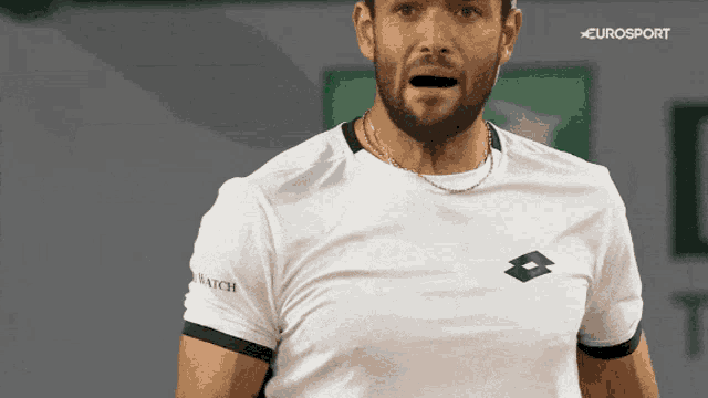 a man with a beard is wearing a white shirt with a lotto logo on the sleeve