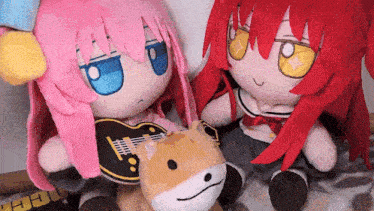two stuffed dolls are sitting next to each other with one holding a guitar