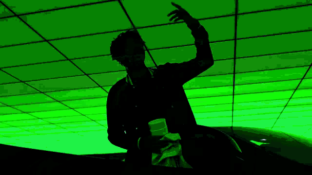 a silhouette of a man sitting on a car in front of a green ceiling .