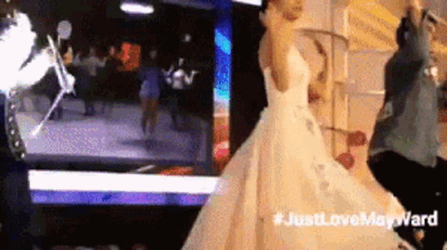 a woman in a wedding dress is dancing with a man in a suit in front of a screen that says just love maryward