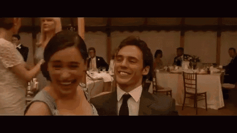 a man and a woman are laughing at a wedding reception while sitting at tables .