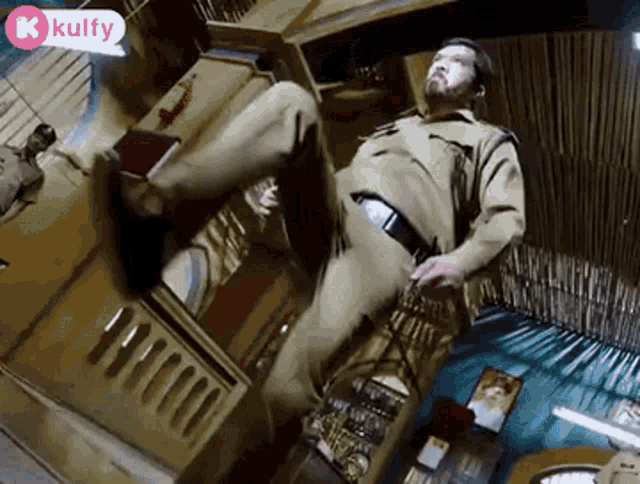 a man in a police uniform is sitting on the floor in a room with his leg up .