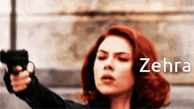 a woman with red hair is pointing a gun at the camera with the name zehra in the corner .
