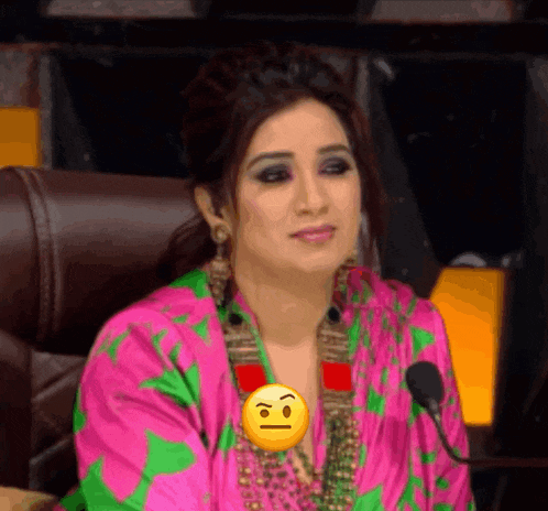 a woman sitting in front of a microphone with a yellow smiley face on her chest