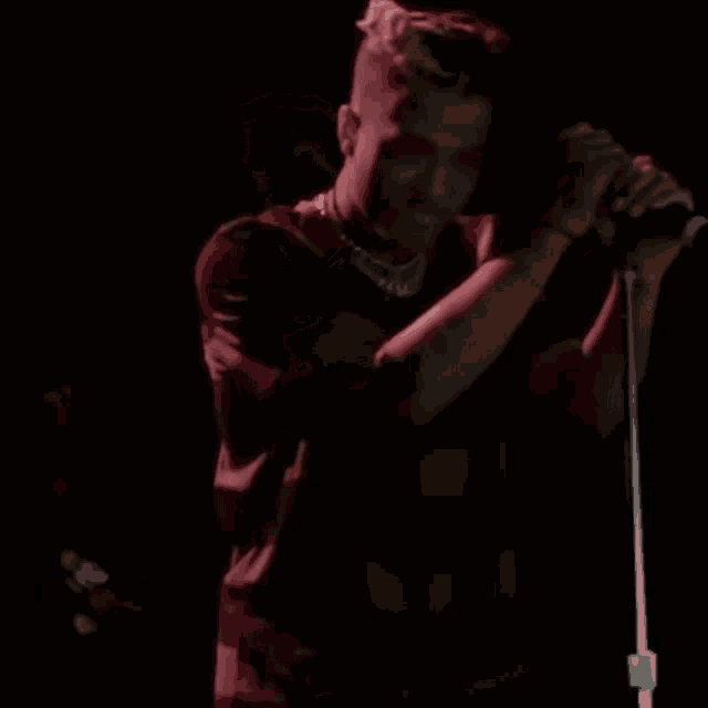 a man singing into a microphone with a necklace around his neck