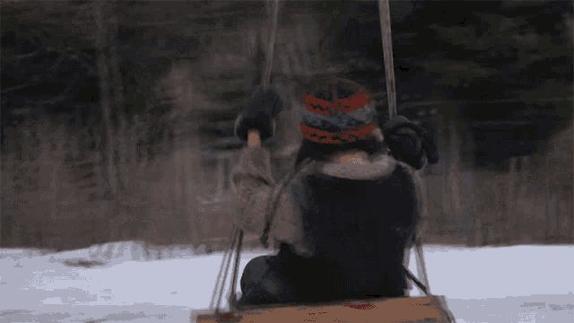 a person sitting on a swing in the snow