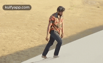 a man in a colorful shirt and black pants is walking barefoot on a white surface .