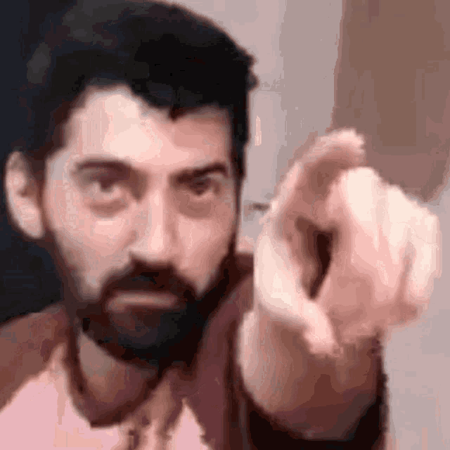 a man with a beard is pointing at the camera with his finger
