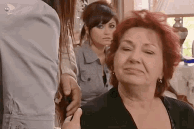 a woman with red hair is sitting in a room with two other women .