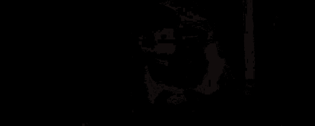 a man with a beard and a hat is standing in front of a mountain .