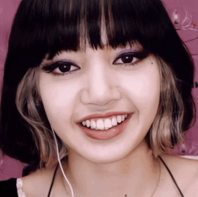 a close up of a woman 's face with a pink wall in the background