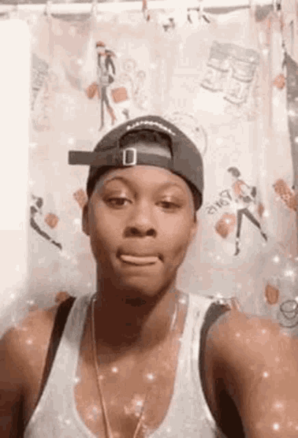a woman wearing a baseball cap and a tank top is making a funny face .