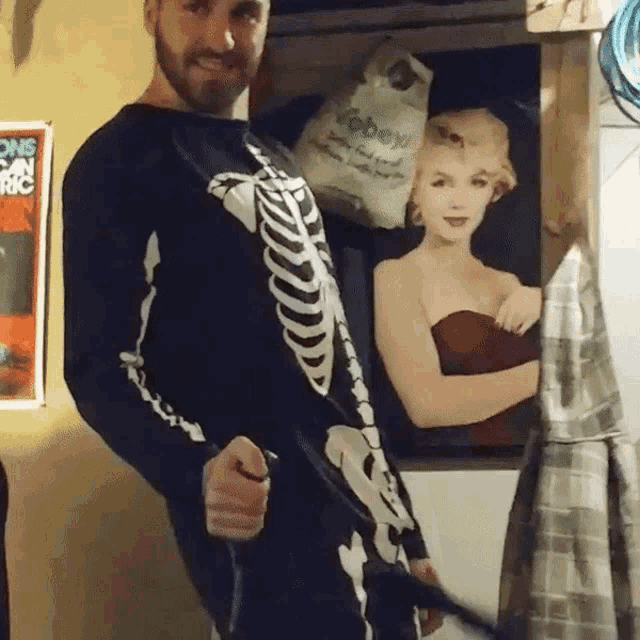a man in a skeleton costume stands in front of a marilyn monroe picture
