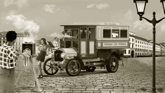 a man taking a picture of a woman standing in front of an old car that says wildungen-film-wildungen on the side
