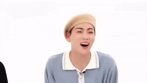 a man wearing a beret is making a funny face and covering his mouth .