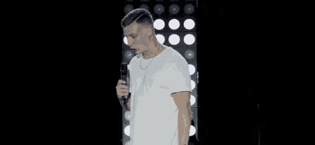 a man is holding a microphone in front of a wall of lights