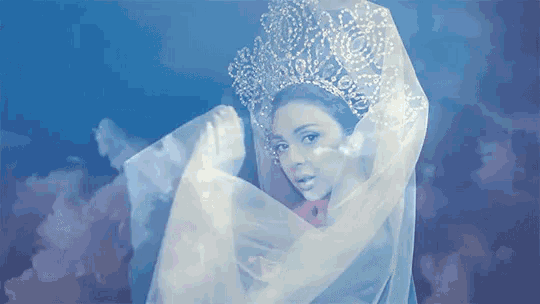 a woman wearing a tiara and veil is dancing in the dark
