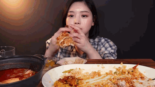 a woman is sitting at a table with a plate of food and eating a sandwich