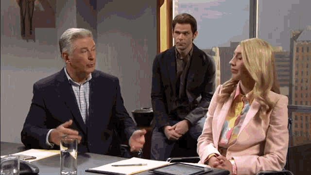a man in a suit and a woman in a pink jacket are sitting at a table